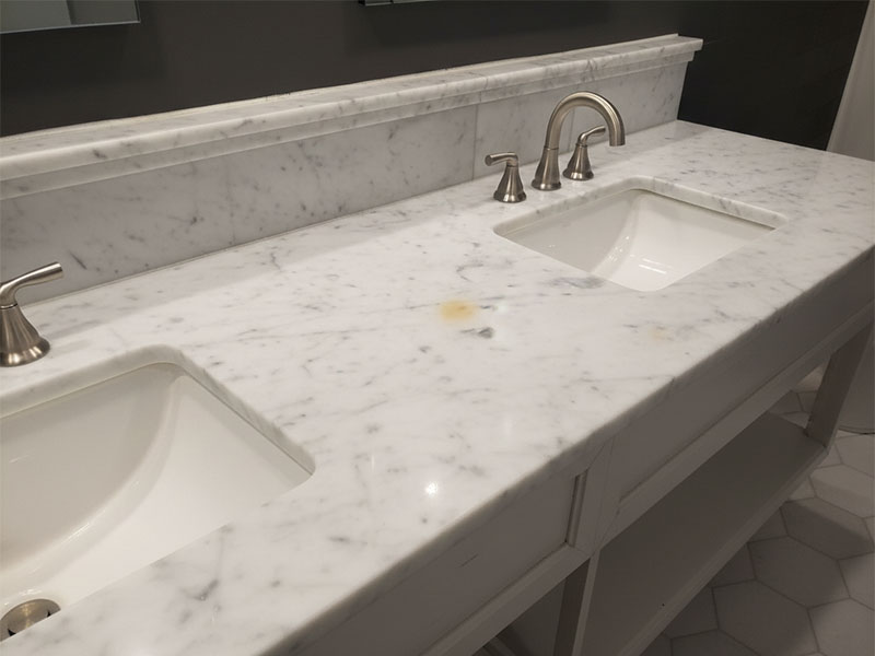White marble vanity with  small yellow stain visible on  surface