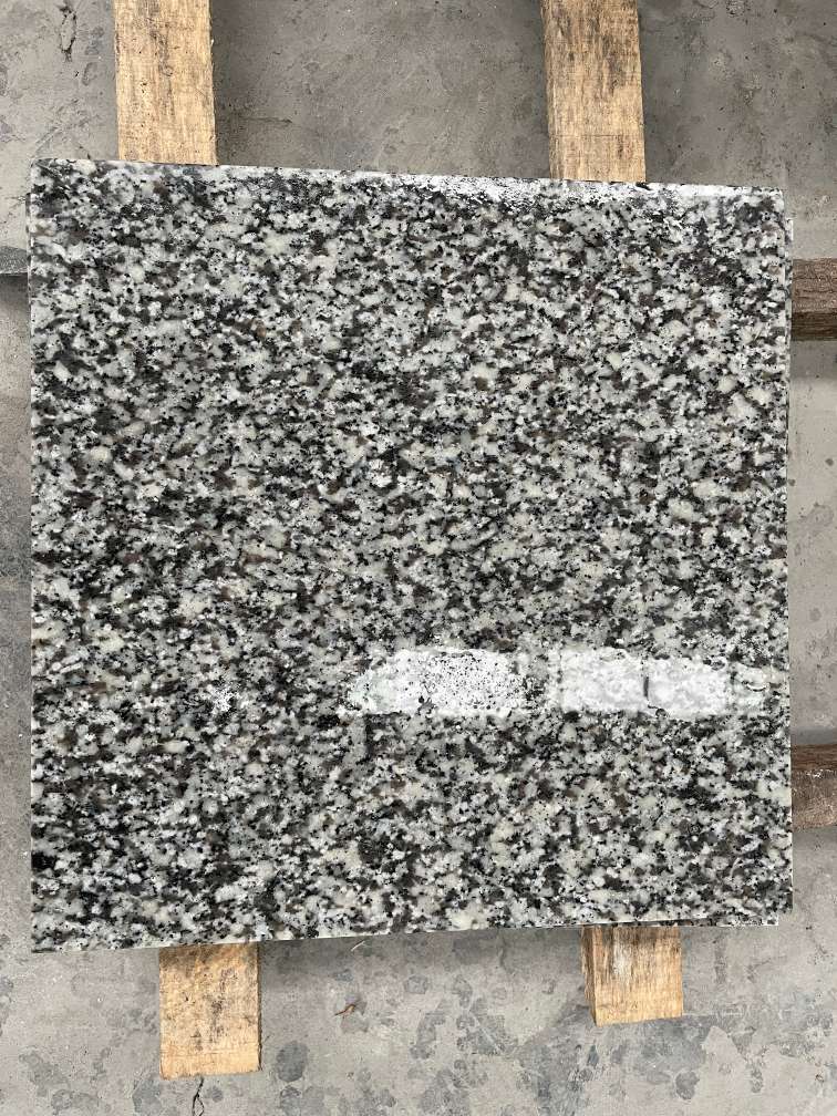 Polished Jilin White granite showing a darker reflective surface than the flamed finish.