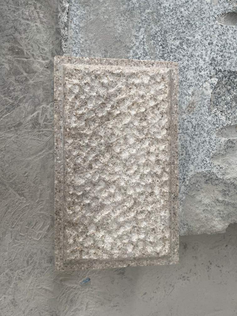 Pineapple-finish granite showing deep chiseled pits for decorative landscape components.