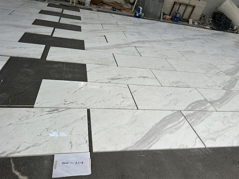 Cut Spider Volakas marble pieces laid out on the floor for slab and vein review