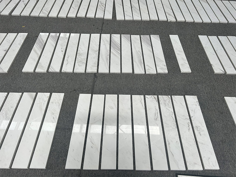 Narrow Volakas marble trim strips pre-laid in groups for dimension and vein sorting